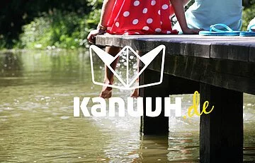 Kanuuh.de Eichstätt Das Logo ein Papierschiffchen mit dem Schriftzug Kanuuh.de. Als Hintergrundbild ein Pärchen, das auf einem Steg sitzt und seine Beine baumeln lässt.