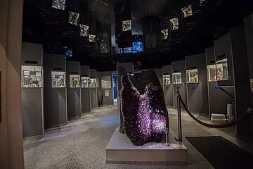Ausstellungsraum des Kristallmuseum Riedenburg Im Vordergrund steht ein großer lilafarbener Kristall. Dahinter rechts und links Vitrinen mit weiteren Exponaten.