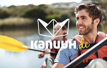 Kanuuh.de Solnhofen Zwei Paddler, ein Mann vorne und eine Frau mit gelben Paddel, deren Gesicht vom Logo einem Papierschiffchen verdeckt wird.