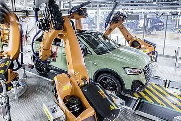 Audi Montage Linie Eine A3 Limousine in hellem pastellgrün ist auf der Montage Linie zusehen. Die Roboterarme arbeiten gerade an dem Fahrzeug.
