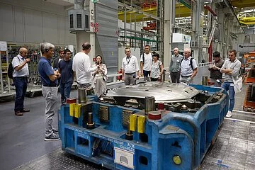 Eine Besuchergruppe steht in der Produktion vor einer Maschine und hört gebannt den interessanten Ausführungen zu.