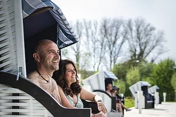 Nahaufnahme von einem Paar das lachend im Strandkorb sitzt.