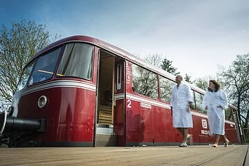 Vor der Schienenbus-Sauna läuft ein Paar im Bademantel