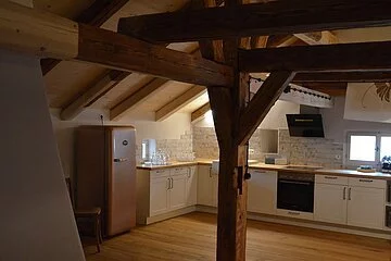 Wohnküche voll ausgestattet in weiß mit Holzplatte.