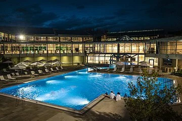 beleuchtetes Außenbecken der Therme bei Nacht