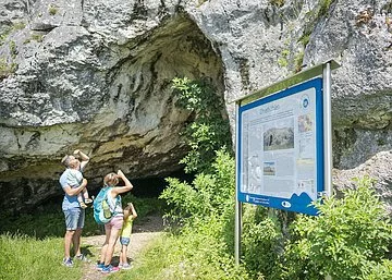 Eine Familie studiert die Infotafel an den Ofnethöhlen.