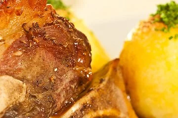 Nahaufnahme einer gebackenen Schweinshaxe mit Knödel und Soße.