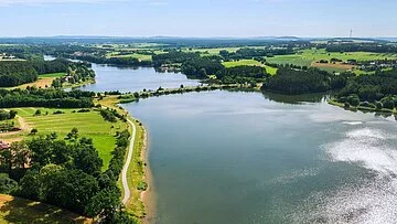 Rothsee Panorama Luftbild von einem Teil des Rothsees. Der See ist umgeben von grünen Wiesen. Entlang des Ufers wachsen viele Bäume und Sträucher.