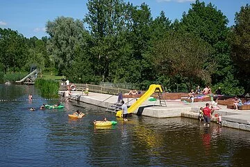 Badende im Wörnitz-Flussfreibad in Oettingen. Auf dem Bild ist auch die Rutsche für die Kinder zu sehen.