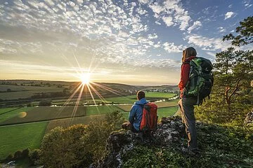 Wanderer auf dem Altmühltal-Panoramaweg genießen den Sonnenuntergang auf dem Burgsteinfelsen