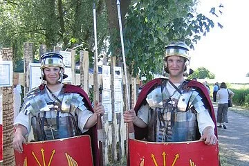 Zwei Männer verkleidet als römische Legionäre. Sie trage eine metallenen Brustpanzer und Helm. Eine Lanze und ein rotes Schutzschild.