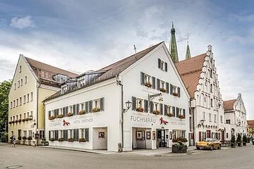 Das Hotel mit 3 Häusern an einer Straßenecke ist zu sehen. Im Hintergrund noch die beiden Türme der Stadtpfarrkirche.