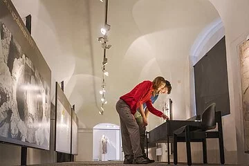 In den Ausstellungsräumen beugen sich zwei Besucher über eine Ausstellungsvitrine.