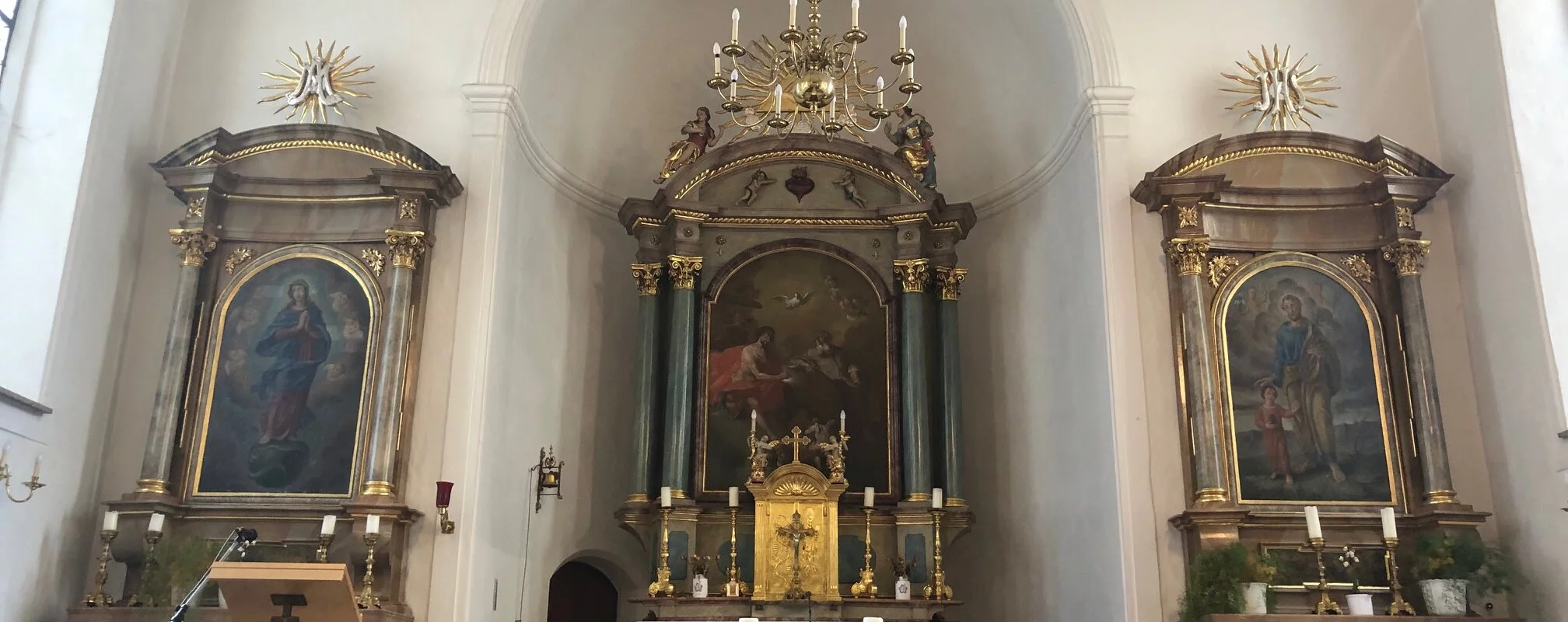 Blick auf den Innenraum der Spitalkirche, mit Hauptaltar und zwei Seitenaltaren.