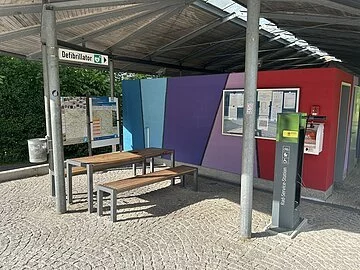 Radreparaturstation am Großparkplatz Unter dem Dach am Großparkplatz steht eine Radreparaturstation mit der man die nötigsten Reparaturen an seinem Fahrrad vornehmen kann. Links ist ein Tisch und zwei Bänke für eine kleine Rast.