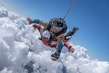 Tandemsprung bei skydive colibri Zwei Tandemspringer bei blauem Himmel oberhalb der Wolkendecke.