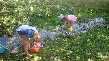 Kinder keschern am Bach