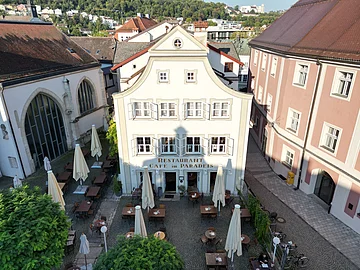 Zu Gast im Café Paradeis in Eichstätt Außenansicht Das Gebäude des Café Paradeis in Eichstätt mit im Vordergrund der Terrasse mit Stühle, Tische und Sonnenschirme.