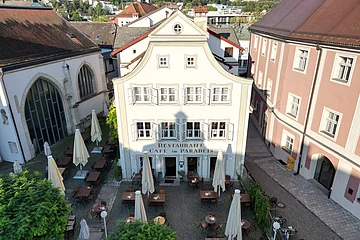 Das Gebäude des Café Paradeis in Eichstätt mit im Vordergrund der Terrasse mit Stühle, Tische und Sonnenschirme.