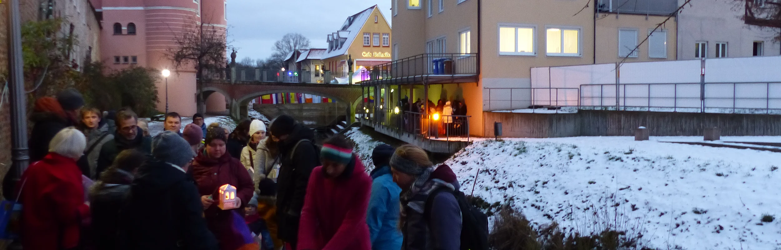 Gruppe von Eltern und Kindern mit Lichterhäuschen (kleinen Papierhäuschen mit Kerze) im Dezember