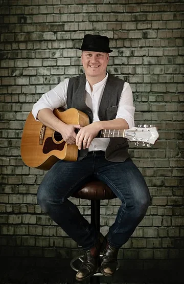 Holm Aktiv Mühle Ein Mann mit Gitarre sitzt auf einem Barhocker