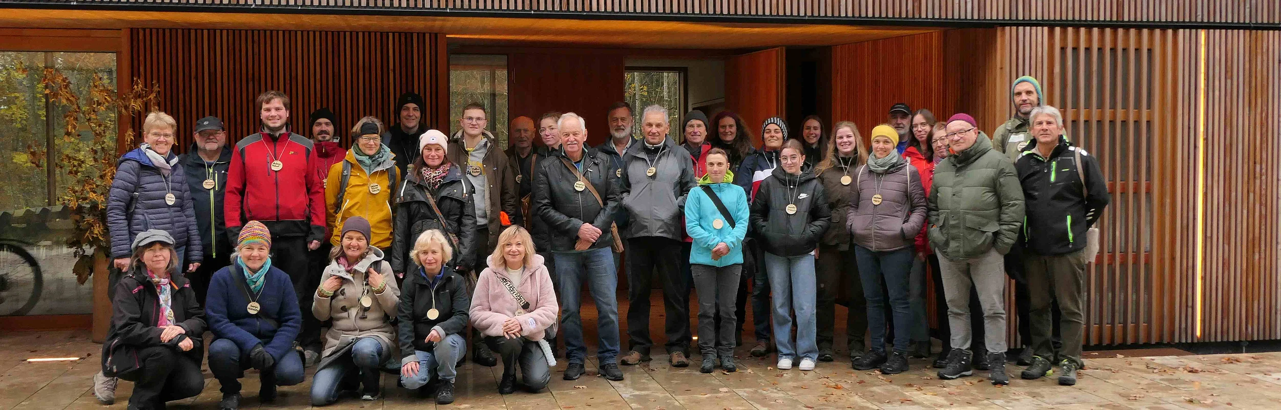 Etwa 30 Naturparkführer stehen vor dem Holzgebäude des Walderlebniszentrums in Schernfeld