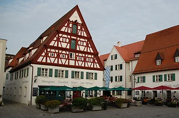 Fachwerkhaus mit grünen Fensterläden und Biergarten davor.