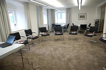 Der kleine Raum ist mit Stühlen ausgestattet, die in einem Stuhlkreis stehen.