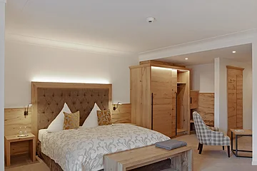 Das Bett aus Holz, sowie die Möbel geben dem Zimmer einen rustikalen Stil.