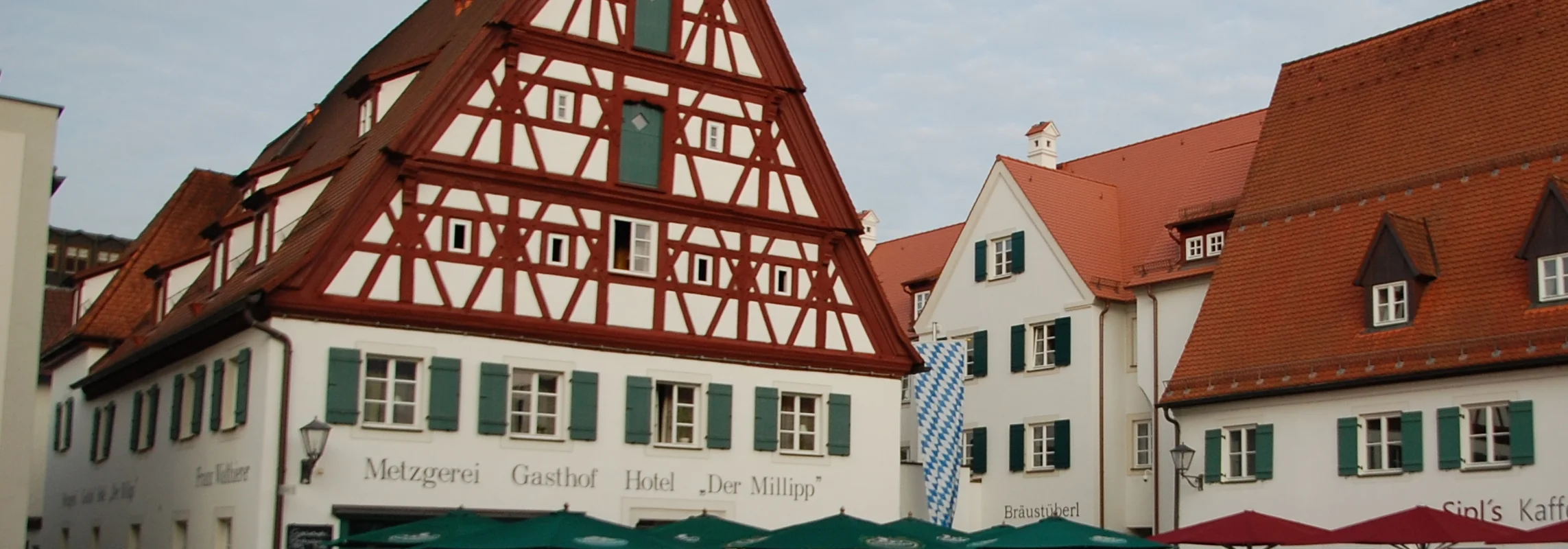 Fachwerkhaus mit grünen Fensterläden und Biergarten davor.