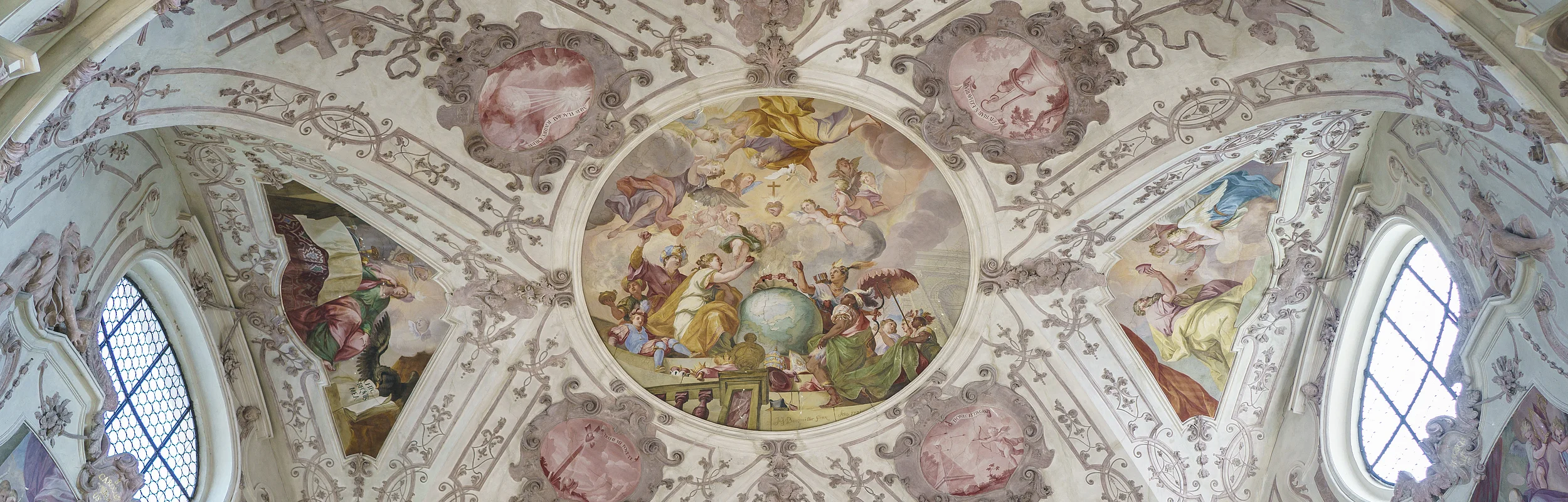 Deckenfresko mit religiösen Szenen und Ornamenten in einer Kirche, umgeben von Fenstern und Stuckverzierungen.