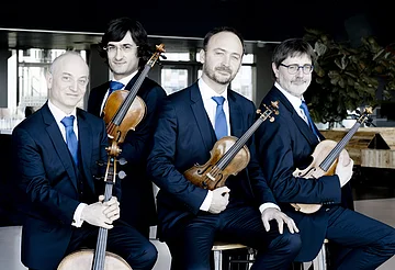 Die vier Musiker des Streichquartetts Quatuor Danel mit ihren Instrumenten sitzend.