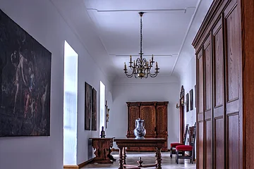 Flur mit weißen Wänden, Kachelfußboden, Holzschränken, Tisch mit Vase und Kronleuchter an der Decke.