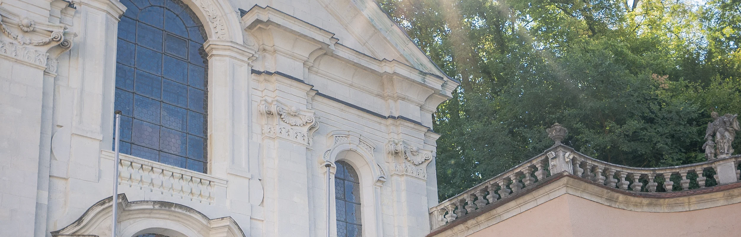 Zwei Frauen und ein Mann stehen vor der Kirche im Klosterinnenhof und bestaunen das Gebäude von außen.