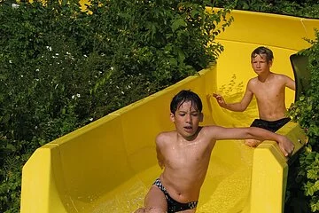 2 Jungen rutschen auf der gelben Wasserrutsche im 7-Täler-Panoramabad.